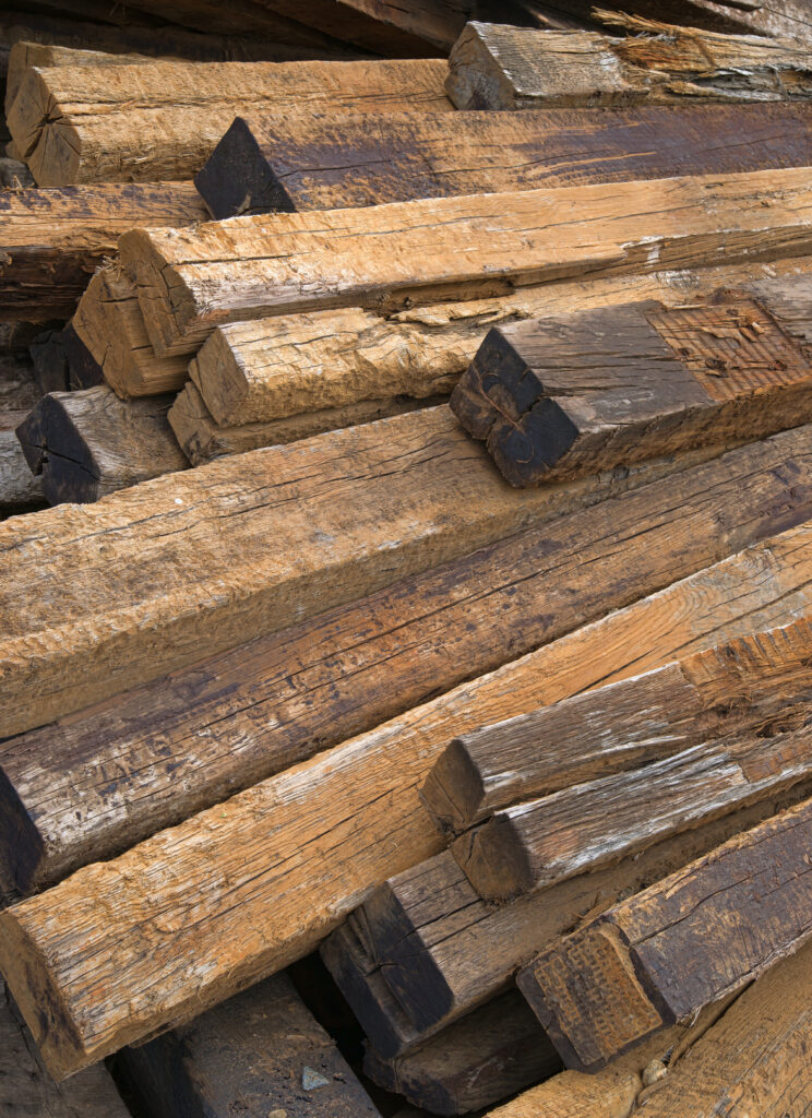 A large pile of used railroad ties left to rot outdoors.